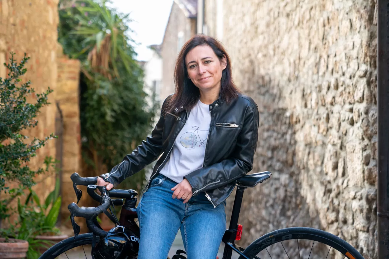 Silvia appoggiata sulla bici con vista panoramica sui tetti di Bibbona