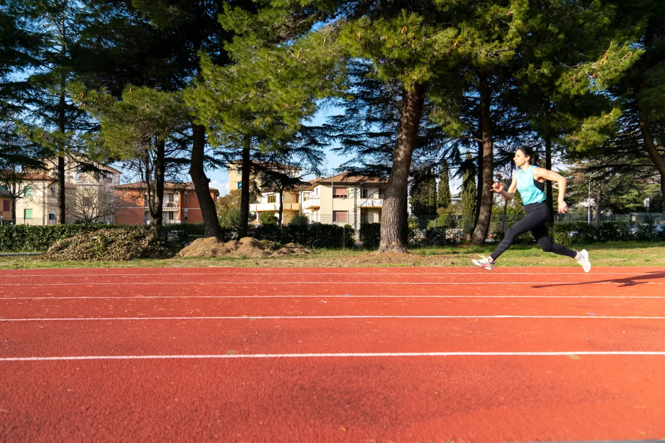 Ritratto sportivo laterale – pista e pini sullo sfondo