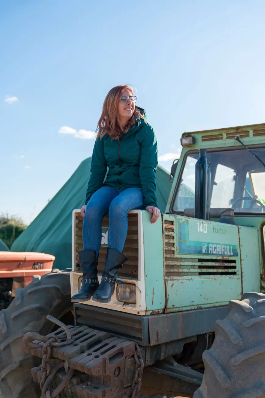 Giulia Filippi seduta sul muso del trattore nel suo agriturismo