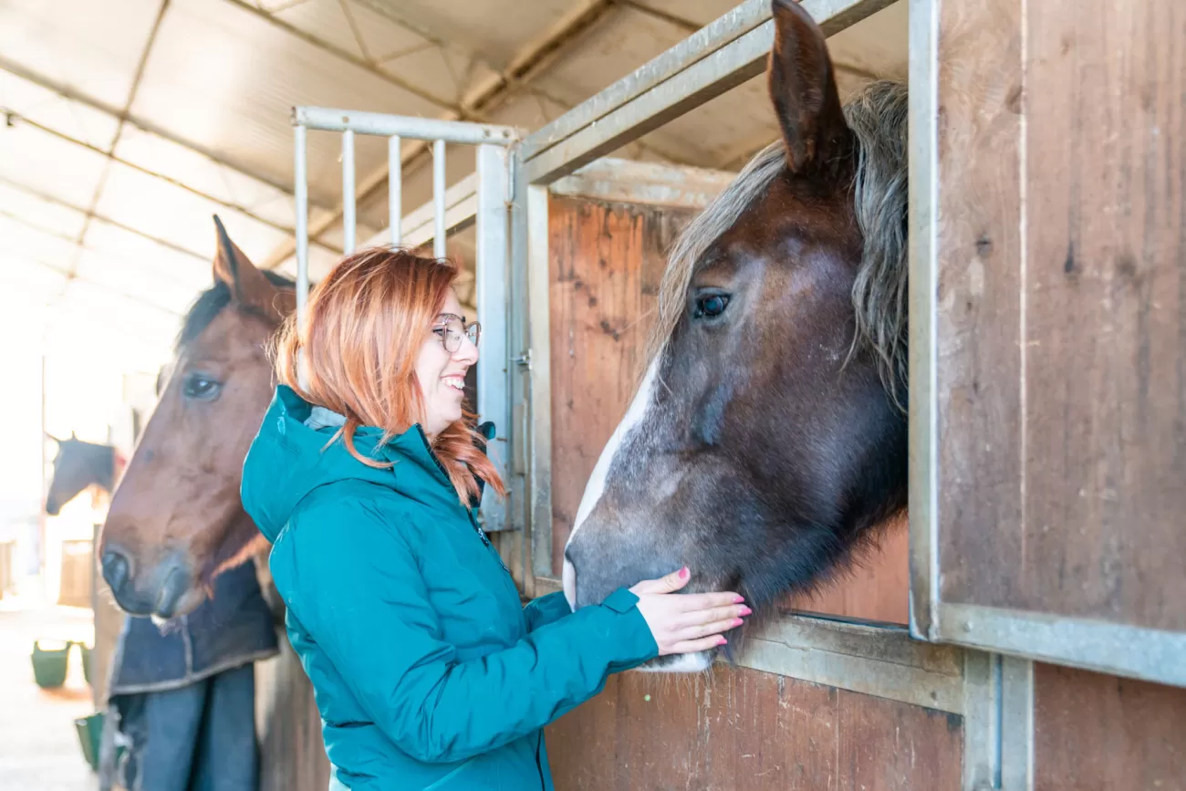 Giulia sorride mentre accarezza un cavallo nella stalla