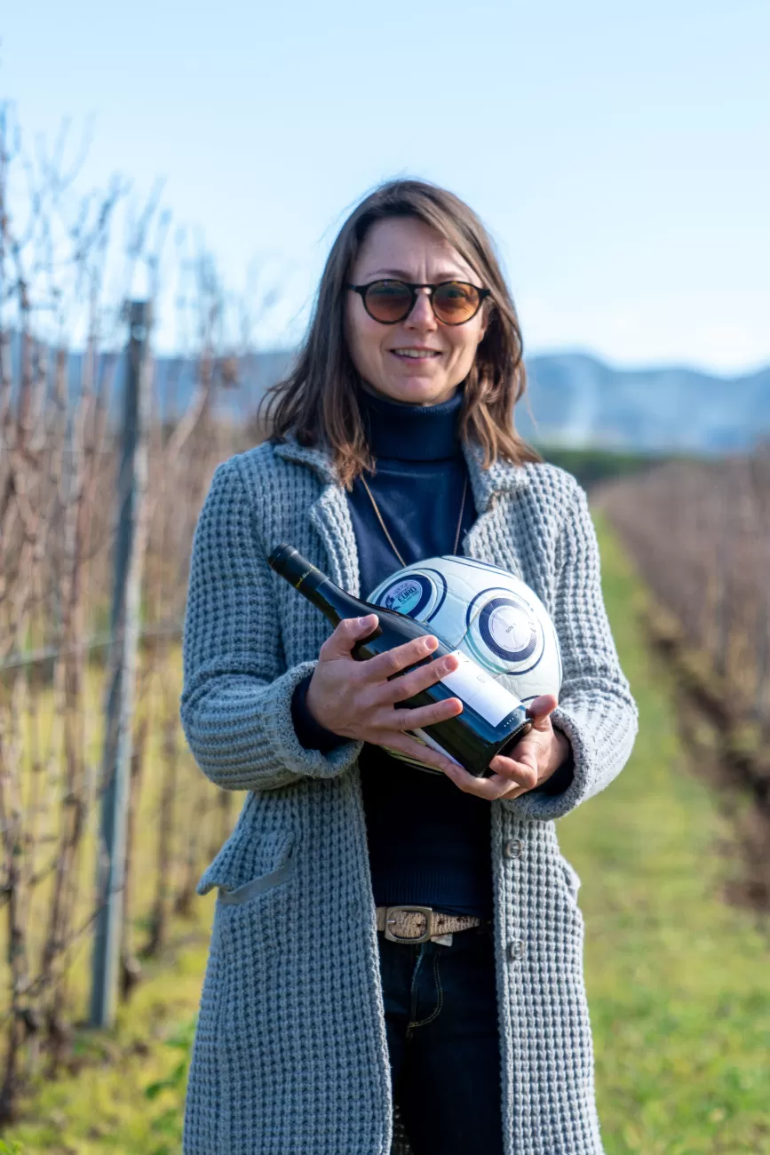 Ritratto ambientato di Silvia Fuselli nei vigneti con vino e pallone 