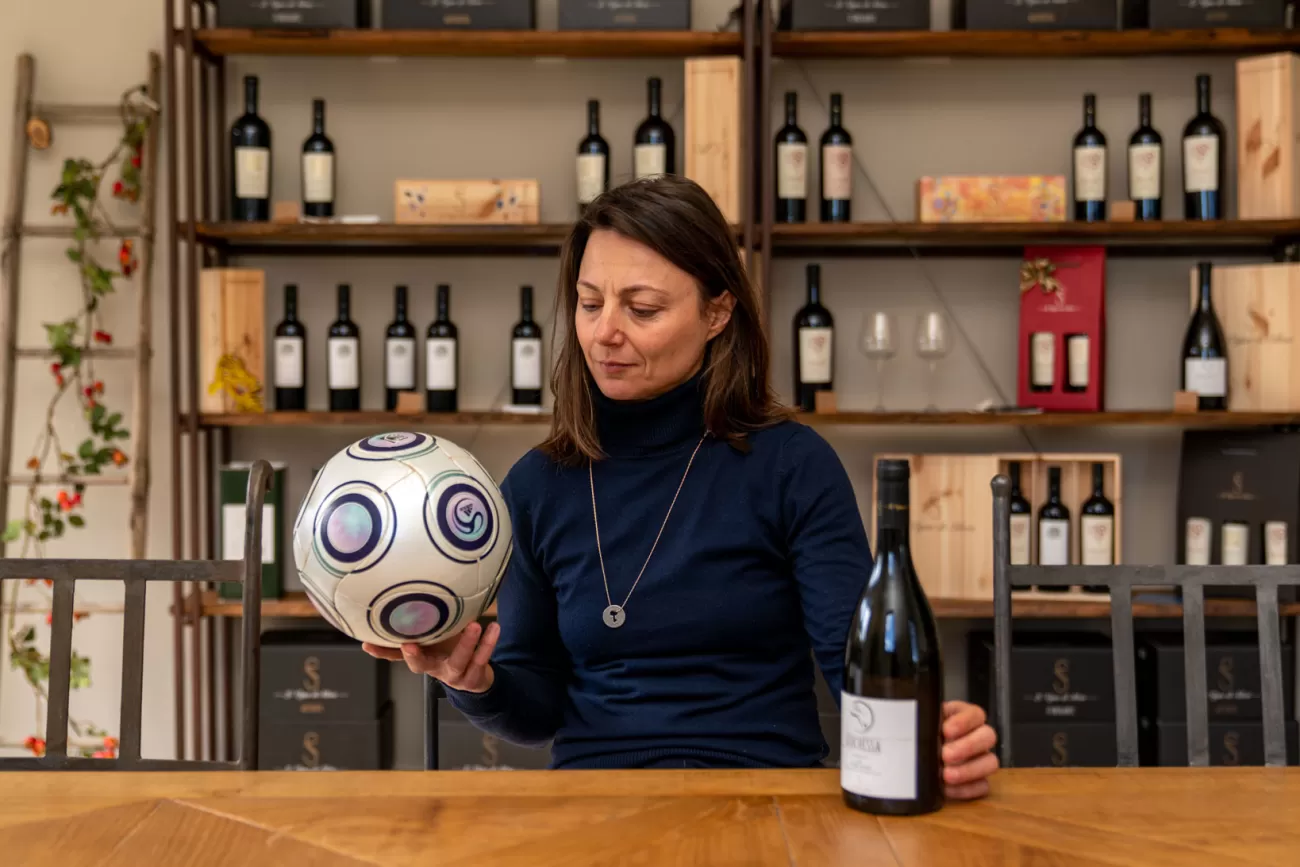 Silvia Fuselli osserva il pallone mentre la bottiglia di vino riposa sul tavolo – momento contemplativo