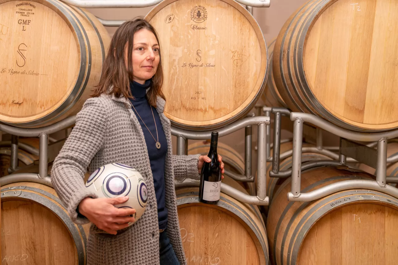 Silvia Fuselli davanti ai botti di legno in cantina – fotografia ambientata per viticoltrici