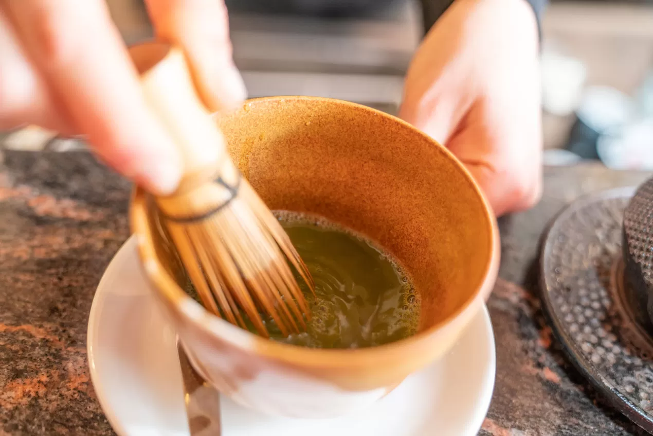 Primo piano della tazza di matcha con frustino – immagine evocativa per branding