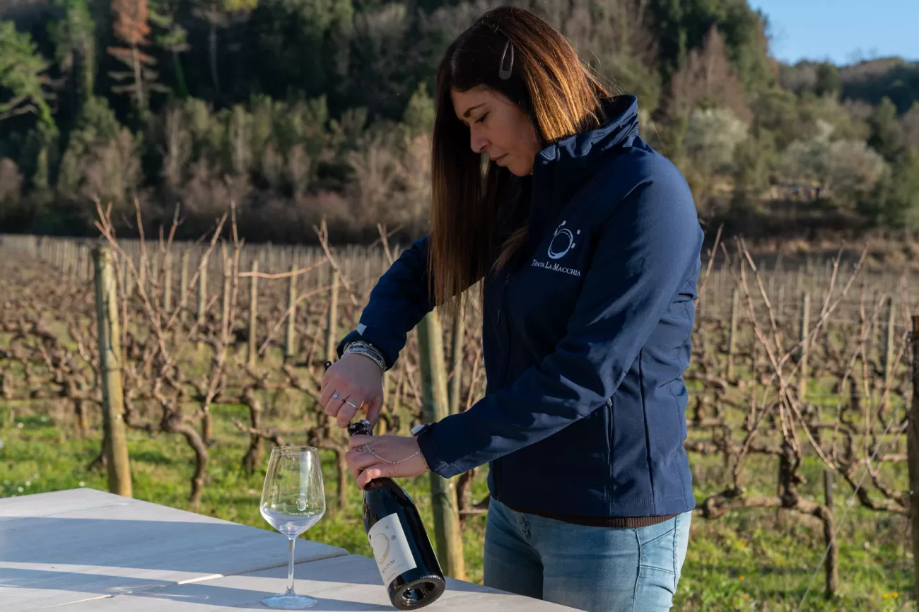 Letizia Martelli apre una bottiglia di vino alla Tenuta La Macchia – preparazione alla degustazione