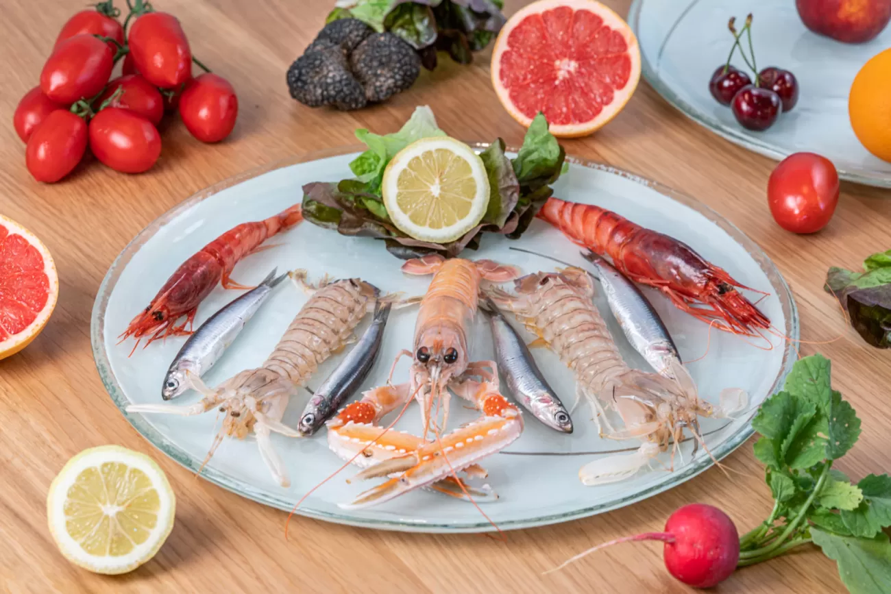 Composizione fotografica di pesci freschi con scampi, cicale, gambero rosso, alici, frutta, verdure e tartufo estivo – fotografia food professionale