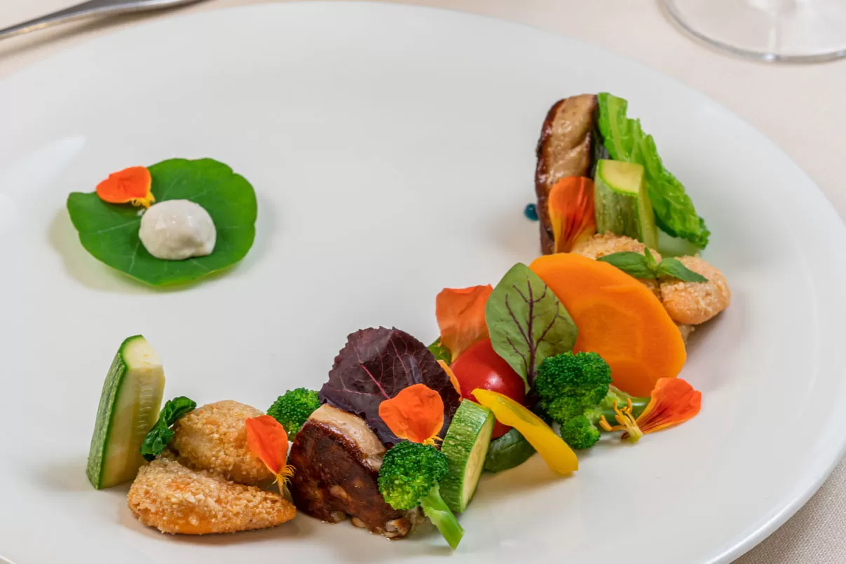Capesante gratinate servite con verdure fresche ed erbe aromatiche