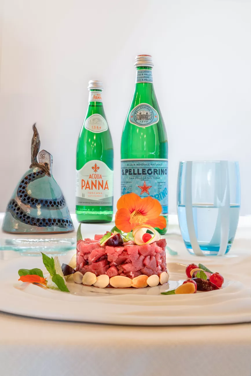 Tartare di tonno con scaglie di mandorle e fiori commestibili – sullo sfondo acqua San Pellegrino – fotografia food premiata nel contest San Pellegrino 2019
