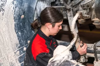 Marta Niccolini lavora con una chiave su un camion privo di ruota, durante una fase di manutenzione